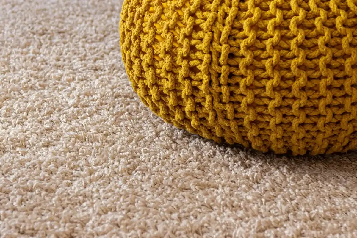Clean cream carpet with a mustard knitted footstool